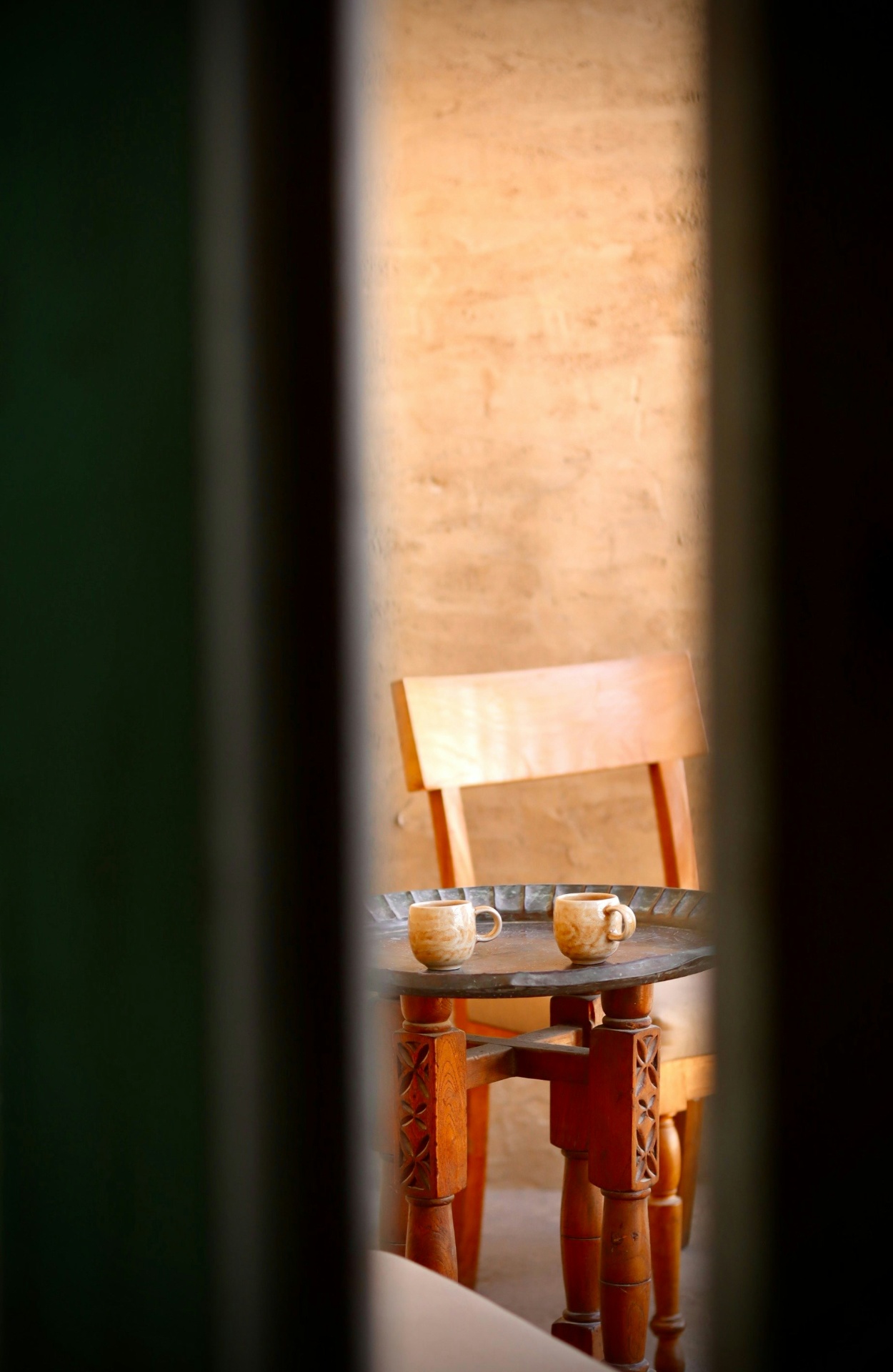 Two cups of tea on a wooden table glimpsed through a doorway