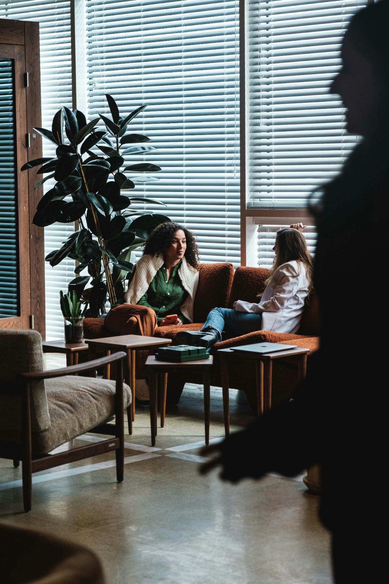 Two people in conversation on a sofa in a light-filled lounge
